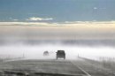 Vehicles make their way through a ground blizzard on a highway leading to Denver