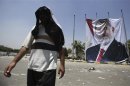 A member of Muslim Brotherhood and supporter of deposed President Mursi walks near huge poster of Mursi after clashes, in Nasr city