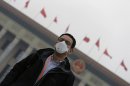 Journalist wearing a mask stands outside the Great Hall of the People after the sixth plenary meeting of the NPC on a hazy day in Beijing