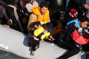 A migrant lifts a child onto a dinghy before travelling &hellip;