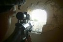 Member of the Free Syrian Army points his weapon through a hole in a wall as he takes up a defense position in a house in Qusseer neighbourhood in Homs