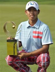 Guan Tianlang of China squats as he holds his winner's trophy during the final day of the Asia-Pacific Amateur Championship at Amata Spring Country Club in Chonburi November 4, 2012. Guan is poised to become the youngest golfer to play at the U.S. Masters after the Chinese 14-year-old won the Asia-Pacific Amateur Championship in Thailand on Sunday. REUTERS/Paul Lakatos/OneAsia/Handout