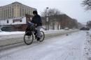 A man holds a coffee while cycling during a winter nor'easter snow storm in Lawrence