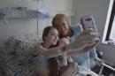 In this Feb 28, 2015 photo released by Chile's Presidential Press Office, Valentina Maureira takes a photo of herself with President Michelle Bachelet, at the Catholic University hospital in Santiago, Chile. The ailing 14-year-old released a video last month in which she asked Bachelet to allow her to be euthanized. Bachelet visited the girl and her family but the government said it could not approve her request. Valentina's father said Sunday, March 22, that people who responded to her plea have led her to change her mind despite her suffering from cystic fibrosis. (AP Photo/Chile Presidential Press Office, Ximena Navarro)
