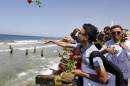 Palestinians throw roses in the Mediterranean sea off the coast of Gaza City on September 18, 2014 in mourning over the loss of fellow Palestinians who had boarded a boat that sank off Malta