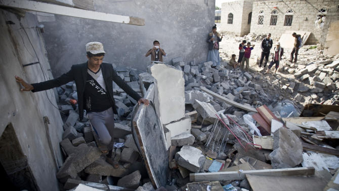 FILE - In this Tuesday, March 31, 2015 file photo, people gather near the rubble of houses destroyed by Saudi airstrikes near the airport in Sanaa, Yemen. Saudi Arabia and its allies plan an ambitious ground offensive on multiple fronts in Yemen. It may be inevitable if they want to defeat Iranian-backed Shiite rebels but it also carries enormous risks, from the inhospitable, mountainous terrain and a possible guerrilla war to al-Qaida militants waiting in the wings. (AP Photo/Hani Mohammed, File)