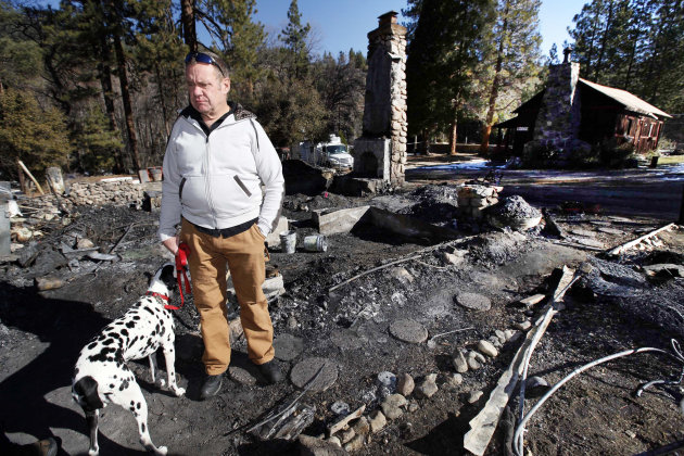 Rick Heltebrake with his dog Suni looks over the burned-out cabin where Christopher Dorner's remains were found after a police standoff Tuesday near Big Bear, Calif., Friday Feb. 15, 2013. Heltebrake had been carjacked by Dorner. (AP Photo/Nick Ut)
