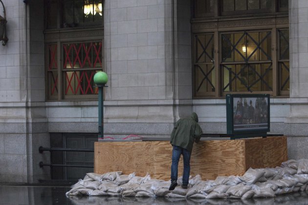 A man peers into a closed subway entrance in downtown Manhattan as Hurricane Sandy makes its approach in New York