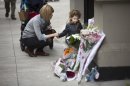 A woman holds a child's hand beside a memorial outside the apartment building where two children were allegedly stabbed by their nanny, Friday, Oct. 26, 2012, in New York. The 2-year-old son and 6-year-old daughter of a CNBC executive were found dead by their mother in a dry bathtub in the family's Upper West Side apartment Thursday night. The nanny suspected of stabbing the children was in critical condition Friday with apparently self-inflicted injuries. (AP Photo/John Minchillo)