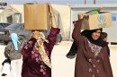 Syrian refugees carry aid and ration at the Zaatari refugee camp in Mafraq