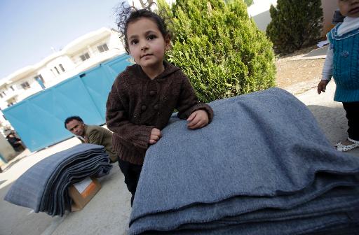 Syrian refugees receive thermal blankets and other humanitarian aid distributed by the UNHCR in preparation for winter at a centre in the Lebanese town of Saadnayel on November 15, 2013