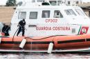 A member of the Italian Coast Guard washes his boat after the recovery of bodies of migrants who were killed in a shipwreck off the Italian coast, in the harbour of the Italian island of Lampedusa on October 7, 2013