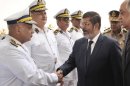 In this photo released by Middle East News Agency, the Egyptian official news agency, President-elect Mohammed Morsi, shakes hands with an Egyptian police general in Cairo, Egypt, Tuesday, June 26, 2012. The military has pledged to turn power over to a civilian government once a new president is named. On Sunday, June 24, 2012, Islamist Mohammed Morsi of the Muslim Brotherhood was declared Egypt's first freely elected president in modern history. (AP Photo/Middle East News Agency, HO)
