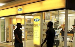 Bystanders walk past an outlet of South Africa&#39;s MTN Group in downtown Cape Town