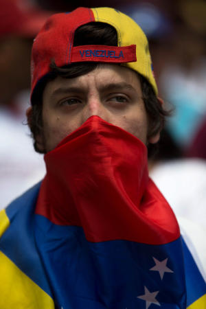 An opposition member covers his face with a Venezuelan &hellip;