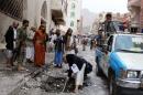 Yemeni civilians, security forces and forensics inspect the site of a car bomb explosion near a mosque on July 29, 2015 in the capital Sanaa