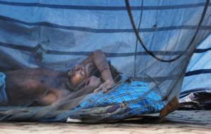 A labour takes a nap under a mosquito net on the pavement …
