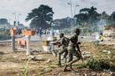 Gabonese soldiers run to take position as supporters of opposition leader Jean Ping protest in front of security forces blocking a demonstration trying to reach the electoral commission in Libreville