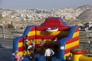 Israeli children play near a construction site during a ceremony to mark the resumption of the construction of housing units in an east Jerusalem neighborhood, Sunday, Aug. 11, 2013. Israel's housing minister on Sunday gave final approval to build nearly 1,200 apartments in Jewish settlements, just three days before Israeli-Palestinian peace talks are to resume in Jerusalem. (AP Photo/Sebastian Scheiner)