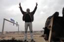 A man flashes the V-sign for victory as he stand on top of a burnt-out lorry on the side of the main highway leading west out of Baghdad to Fallujah, on January 5, 2014