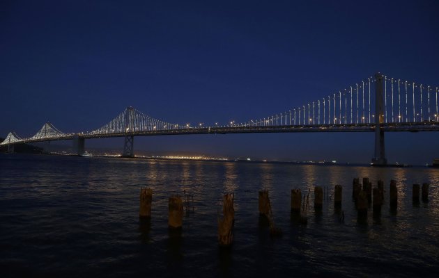 In this Wednesday, Feb. 20, 2013, photo,lights are turned on along the western half of the San Francisco-Oakland Bay Bridge on Pier 14 in San Francisco. The San Francisco-Oakland Bay Bridge has been turned into the latest, and by far the biggest, backdrop for New York artist Leo Villareal, who has individually programmed 25,000 white lights spaced a foot apart on 300 of the span’s vertical cables to create what is being billed as the world’s largest illuminated sculpture. (AP Photo/Jeff Chiu)