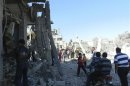 Residents walk among damaged buildings after a Syrian Air Force fighter jet loyal to Syria's President Bashar al-Assad fired missiles at Houla, near Homs
