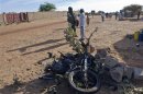 A soldier points his finger at the wreckage of a motorbike used by a suicide bomber who blew himself up at a checkpoint north of Gao