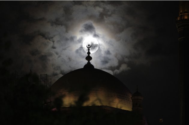 A full moon is seen behind the minaret of Mohamed Ali mosque, in Islamic Cairo