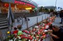 People light candles beside flowers laid in front of the Olympia shopping mall, where yesterday's shooting rampage started, in Munich