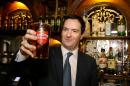 British Chancellor of the Exchequer George Osborne holds up a pint of beer in Westminster, central London, February 25, 2014