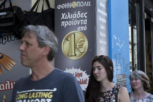 Tourist walks past a discount shop which reads in Greek&nbsp;&hellip;