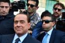 Former Italian prime minister Silvio Berlusconi (L) leaves the central justice office in Milan surrounded by his security guards on April 23, 2014
