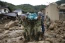 JSDF soldiers and police officers carry the body of a victim in a plastic bag at a site where a landslide swept through a residential area at Asaminami ward in Hiroshima