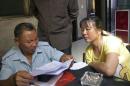 Farmer Li and his neighbours look through a list of local residents with elevated levels of lead in their blood, in Dapu