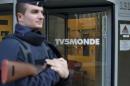 A French police officer stands guard in front of the main entrance of French television network TV5Monde headquarters