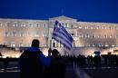 A man holds a Greek flag in front of the parliament in Athens as people gather in support to their government on February 20, 2015
