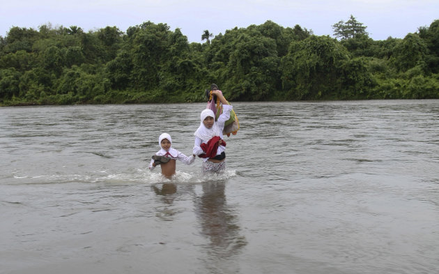 Elementary school girls cross a river to go to school in the village of Nagari Koto Nan Tigo in Indonesia's West Sumatra province