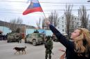 A pro-Russian supporter waves a Russian flag in front of pro-Russian armed men in military fatigues blocking the base of the Ukrainian frontier guards, in Balaklava, a small city not far from Sevastopol, on March 1, 2014