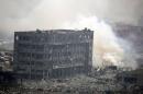 Smoke rises next to a damaged building at the site of the explosions at the Binhai new district in Tianjin