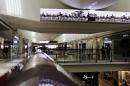In this photo taken Wednesday, April 15, 2015, shoppers stroll through a mall in Riyadh, Saudi Arabia beneath an electronic billboard showing images of soaring F-16s and King Salman saluting the troops. 
