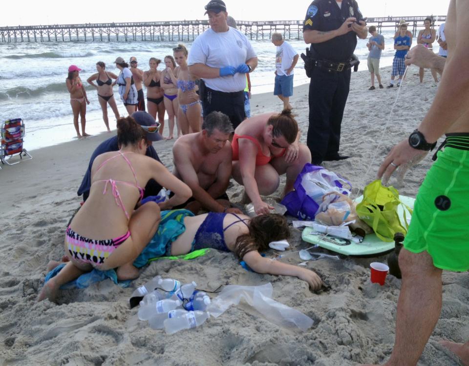 Emergency responders assist a teenage girl at the scene of a shark attack in Oak Island, N.C., Sunday, June 14, 2015. Mayor Betty Wallace of Oak...