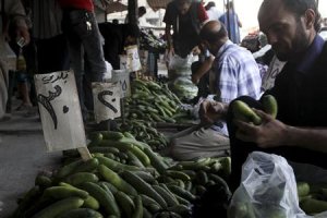 A man buys cucumbers at a souk in Aleppo
