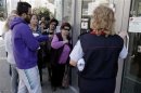 Customers queue up outside a branch of Laiki Bank as they wait for the reopening of the bank in Nicosia