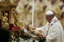 Pope Francis holds a statue of baby Jesus as he celebrates the Christmas Eve Mass in St. Peter's Basilica at the Vatican, Tuesday, Dec. 24, 2013. (AP Photo/Gregorio Borgia)