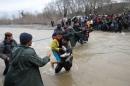 Migrants wade across a river near Greek-Macedonian border west of Idomeni