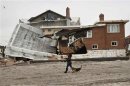 A woman walks by a home destroyed by the effects of Hurricane Sandy in the Belle Harbor section of the Queens borough in New York