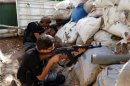 Free Syrian Army fighters take up positions behind piled sandbags as they aim their weapons in the eastern al-Ghouta, near Damascus