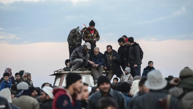 Men stand on a roof of a vehicle as Syrians fleeing the northern embattled city of Aleppo wait on February 5, 2016 in Bab-Al Salama, near Turkish crossing gate