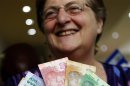South African Reserve Bank Governor Gill Marcus smiles as she shows off South Africa's new banknotes before conducting the first transaction in Pretoria