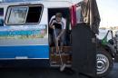 In this Sunday, July 6, 2014 photo, Argentine Jose Ribeti, 29, sweeps the stairs of his bus "Carnavalito," in the Granja do Torto parking lot used by traveling World Cup soccer fans as a campground, in Brasilia, Brazil. Ribeti is part of a group of Argentine men who has spent the last month traveling all over Brazil in a converted bus to watch their national soccer squad's progress during the World Cup. (AP Photo/Rodrigo Abd)